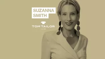Person smiling, wearing a white blazer and large earrings, with text 'SUZANNA SMITH' and 'TOM TAILOR'.